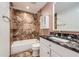 Updated bathroom features a shower-tub combination with decorative tile and granite countertop at 8220 Lamar Cir, Arvada, CO 80003