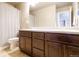Bathroom with dual sinks, wood cabinets, and a shower with a curtain for privacy at 802 Gamble Oak St, Brighton, CO 80601