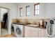 Well-equipped laundry room with front-load washer and dryer, sink, cabinets, and closet access at 2430 Marlin Way, Castle Rock, CO 80109