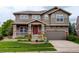 Charming two-story home with a well-maintained lawn, inviting porch, and an attached two-car garage at 14200 W 86Th Pl, Arvada, CO 80005