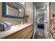 Bathroom with a wooden vanity, sink, and a view into the main bedroom at 8258 S Reed Way, Littleton, CO 80128