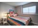 Bedroom with window, colorful patterned bedding, a nightstand, and a lamp at 8258 S Reed Way, Littleton, CO 80128