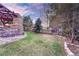 Beautifully landscaped backyard with a stone wall, a pergola, mature trees, and lush green lawn at 10459 Rivington Ct, Lone Tree, CO 80124