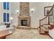Cozy living room features a stone fireplace, staircase, and large windows at 10459 Rivington Ct, Lone Tree, CO 80124