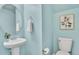 Charming powder room with a pedestal sink, round mirror, and coordinating blue walls at 8065 E 21St Ave, Denver, CO 80238