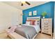 Stylish bedroom featuring a bold blue accent wall, white furniture, and cozy decor at 8065 E 21St Ave, Denver, CO 80238