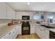 Bright kitchen features white cabinets, a black oven and microwave, and a window with natural light at 600 Balsa Dr, Castle Rock, CO 80104