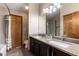 Bathroom featuring a double vanity with granite countertop and a shower with glass doors at 7636 S Allison Ct, Littleton, CO 80128
