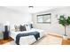 Bright bedroom features a queen bed with white bedding, blue accents, and a cozy rug on hardwood floors at 4300 Osage St, Denver, CO 80211
