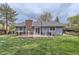 Backyard with a wooden deck, brick chimney, well-maintained lawn, mature trees, and a gray painted home at 10723 Cherry Ct, Thornton, CO 80233