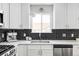 Modern kitchen features white cabinets, a large sink, and dark tile backsplash at 1531 W Dakota Ave, Denver, CO 80223