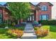 Beautiful brick home featuring a landscaped front yard with colorful flowers and a charming entrance at 5672 S Nome St, Englewood, CO 80111