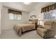 Comfortable bedroom with two windows, a bed, recliner chair and neutral tones at 6832 S Birch Way, Centennial, CO 80122