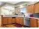 A kitchen with wood cabinets, stainless steel appliances, tile backsplash, and a large window overlooking the front yard at 4 Prairie Falcon Ln, Littleton, CO 80127