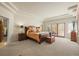 A spacious carpeted bedroom featuring tray ceilings, french doors with plantation shutters, and dark wood furniture at 4 Prairie Falcon Ln, Littleton, CO 80127