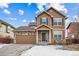 Two-story house with brown siding, stone accents, and a two-car garage at 11590 River Oaks Ln, Commerce City, CO 80640
