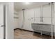 Bright laundry room features a utility sink, white shelving, and durable floors at 6699 S Pennsylvania St, Centennial, CO 80121