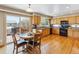 Bright kitchen features wood floors, wood cabinets, black appliances and a dining area with sliding door to deck at 4901 Ashbrook Cir, Highlands Ranch, CO 80130