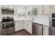Bright kitchen features stainless appliances, white cabinets, solid surface countertops, and wood flooring at 10309 W Fair Ave # E, Littleton, CO 80127