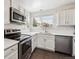 Modern kitchen with stainless steel appliances, white cabinets, and a large window at 10309 W Fair Ave # E, Littleton, CO 80127