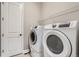 Functional laundry room featuring modern washer and dryer, with overhead wire rack for added storage at 7693 S Quantock Way, Aurora, CO 80016
