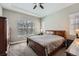 A comfortable primary bedroom with tray ceilings, a ceiling fan, and a large window at 7693 S Quantock Way, Aurora, CO 80016