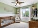 A cozy Bedroom features a wooden crib, comfortable chair, and ample natural light from a window at 8450 E 29Th Ave, Denver, CO 80238
