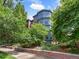 Brick home with blue trim featuring manicured landscaping, brick retaining wall, and mature trees at 8450 E 29Th Ave, Denver, CO 80238