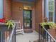 Covered front porch featuring flower planters, rocking chair, black railing, and brick exterior at 8450 E 29Th Ave, Denver, CO 80238