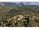 Expansive aerial view showcasing a log home surrounded by dense forest and rolling hills at 2518 N State Highway 67, Sedalia, CO 80135