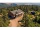 Stunning log home featuring an outdoor deck and a two-car garage nestled amid lush green trees and mountain scenery at 2518 N State Highway 67, Sedalia, CO 80135