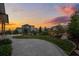 Serene backyard with a lush lawn, mature trees, rock features, and beautiful sunset views at 6696 Kenzie Cir, Castle Pines, CO 80108