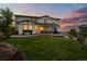 Picture-perfect backyard with a lush lawn, covered patio, hot tub, and beautifully designed landscaping at 6696 Kenzie Cir, Castle Pines, CO 80108