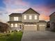 Two-story home boasting a stone facade, three-car garage, and well-manicured lawn at twilight at 5842 High Timber Cir, Castle Rock, CO 80104