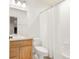 Bright bathroom with wooden vanity, white toilet, and shower with a textured curtain at 6700 W Dorado Dr # 41, Littleton, CO 80123