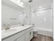 Well-lit bathroom featuring double vanity, white cabinets and countertops, and a tiled bathtub at 9277 Truckee Ct, Commerce City, CO 80022