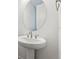 Elegant pedestal sink with oval mirror and modern fixtures in a bright, minimalist bathroom at 9277 Truckee Ct, Commerce City, CO 80022