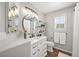 Well-lit bathroom features a round mirror, floating shelves, and a white vanity with black hardware at 6242 Shea Pl, Highlands Ranch, CO 80130