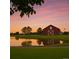 Charming red barn with a tranquil pond and a picturesque sunset backdrop at 10995 Quintero St, Commerce City, CO 80022