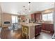 Bright kitchen featuring a spacious island with granite countertops, stainless steel appliances, and hardwood floors at 10995 Quintero St, Commerce City, CO 80022