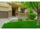 Inviting front porch with stone pillars and decorative railing, complemented by lush landscaping and manicured lawn at 10995 Quintero St, Commerce City, CO 80022