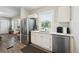 Bright kitchen features stainless steel appliances, white cabinets, and a view to the entry at 1456 Syracuse St, Denver, CO 80220