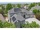 An aerial view showcases a house with solar panels, a stone facade, and green trees at 6553 S Sedalia St, Aurora, CO 80016
