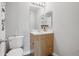 Neutral bathroom featuring a wood vanity, white countertop, framed mirror, and a view into another room at 6553 S Sedalia St, Aurora, CO 80016