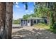 Charming single-story home with blue siding and gravel driveway, surrounded by lush greenery and mature trees at 5725 W Mississippi Ave, Lakewood, CO 80226