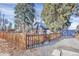 View of a charming blue home with a wood fence, gravel driveway, and mature trees at 5725 W Mississippi Ave, Lakewood, CO 80226