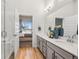 Bright bathroom featuring double vanity sinks, modern lighting, and a view into the main bedroom at 487 Interlocken Blvd # 104, Broomfield, CO 80021