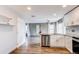 Bright kitchen with white cabinets, wood floors, stainless steel dishwasher, and gray walls at 3607 Dinosaur St, Castle Rock, CO 80109