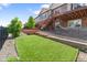 Landscaped backyard with synthetic grass, stone retaining wall, deck with stairs and hammock at 7410 S Old Hammer Way, Aurora, CO 80016