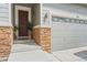 Inviting front entry with dark wood door, stone accents, and stylish outdoor lighting at 7410 S Old Hammer Way, Aurora, CO 80016